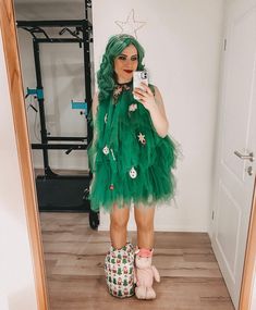 a woman with green hair is taking a selfie in the mirror while holding her cell phone