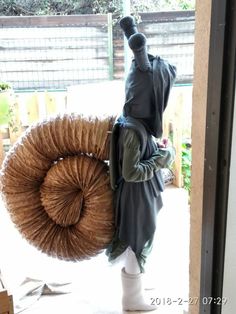 a person standing in front of a door holding a large bundle of straw on his back