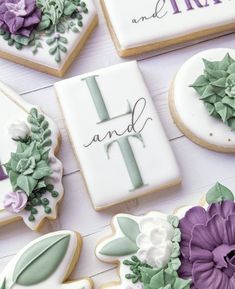 some decorated cookies are on a table with purple and green flowers in the middle one cookie is shaped like a cross