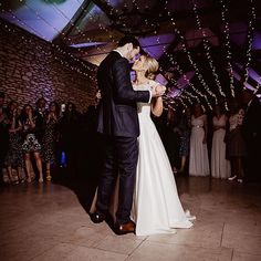 a bride and groom share their first dance at their wedding reception in front of an audience