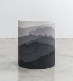 a black and white mug sitting on top of a table with mountains in the background