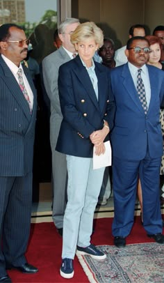 two men in suits and ties standing next to each other on a red carpeted area