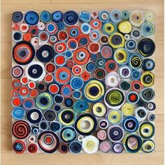 an art work made out of rolled up paper on a wooden floor with circles in the middle