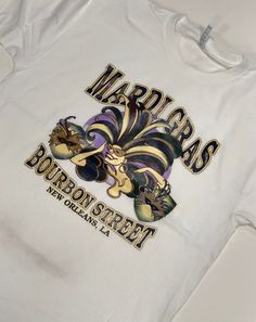 Laissez les bon temps rouler! This t-shirt features a woman's face wearing a Mardi Gras mask and reads "Mardi Gras Bourbon Street New Orleans LA" Product is available in Black and is offered sizes S-6XL Bourbon Street New Orleans, Feather Mask, Mardi Gras Shirt, Beaded Hat, Mardi Gras Beads, Polo Shirt Dress, Bourbon Street, Mardi Gras Mask, Night Shirt