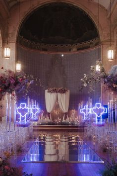 an indoor wedding setup with candles and flowers on the floor, surrounded by clear chairs