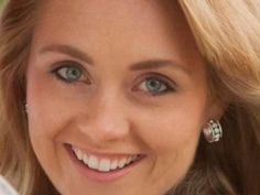 a close up of a woman with blue eyes and blonde hair smiling at the camera