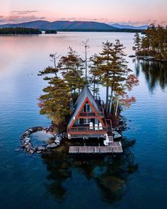 an island with a house on it in the middle of water and trees around it