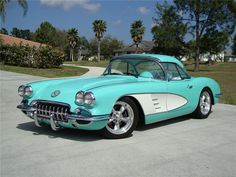 a turquoise and white car parked in a driveway