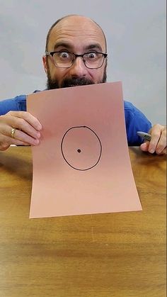 a man sitting at a table with a piece of paper in front of his face