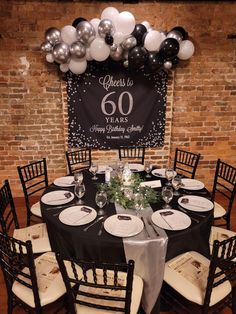 a black and white table set up for a 60th birthday party with balloons on the wall