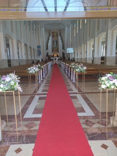 a red carpeted aisle with flowers and candles at the end is lined up in front of pews