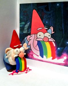 a gnome with a rainbow colored toy next to a painting on a white table top