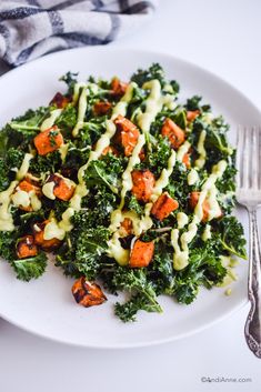 a white plate topped with broccoli and carrots next to a silver fork