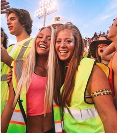 two girls and one boy are standing in front of a crowd at a football game