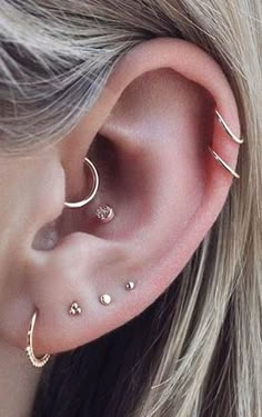 a woman's ear with three different piercings