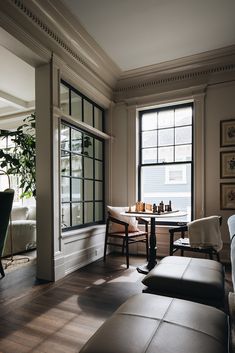 a living room filled with furniture next to two large windows and a table in front of it