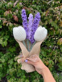 a hand holding some purple flowers in burlock