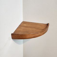 a wooden shelf mounted to the side of a wall next to a white painted wall