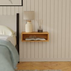 a bed room with a neatly made bed and a night stand on the wall next to it