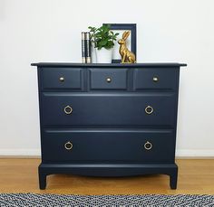 a blue dresser with gold handles and knobs on it in front of a white wall