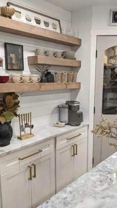 a kitchen with white cabinets and marble counter tops in the center is decorated with gold accents