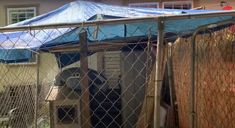 an outdoor area with a blue tarp on the roof and a fence surrounding it