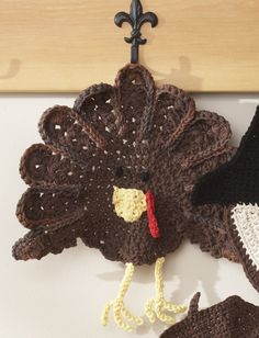 a crocheted turkey hanging from a hook on a wooden wall next to scissors