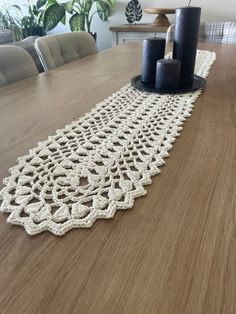 the table runner is made from crochet and has two candles on top of it