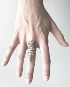 a person's hand with a small tattoo on the middle of their ring finger