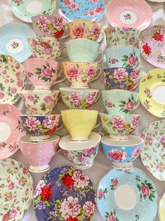 there are many plates and bowls on the table with flowers painted on them, all in different colors