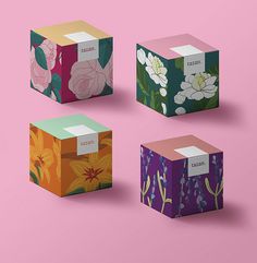 four colorful boxes with flowers on them against a pink background