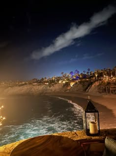 a candle is lit on the edge of a cliff overlooking the ocean and beach at night