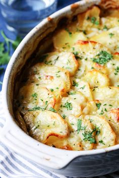 a casserole dish with potatoes and parsley in it on a blue table cloth