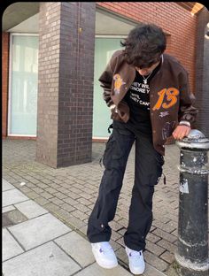 a person leaning against a pole on the sidewalk