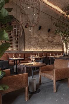 a restaurant with tables, chairs and plants in the middle of the room on either side of the table is a chandelier that hangs from an old brick wall