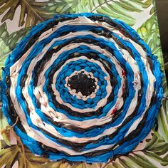 a blue, white and black circular object sitting on top of a leafy table