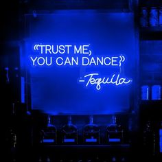 a neon sign that says trust me, you can dance tequila in front of liquor bottles