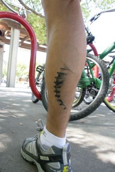 a man with a tattoo on his leg standing in front of some bikes and bicycles