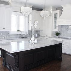 a large kitchen with white cabinets and marble counter tops, along with an island in the middle