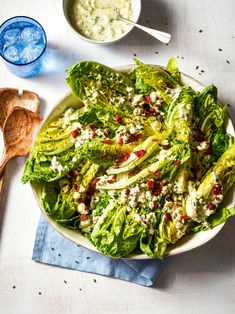 a salad with lettuce and feta cheese in a bowl next to a spoon