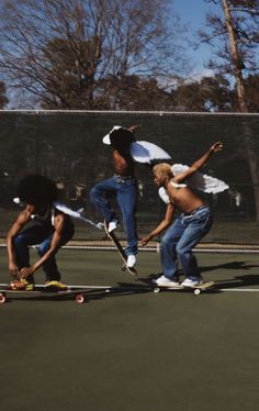 three skateboarders doing tricks on a tennis court