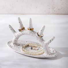 a white ceramic sculpture with gold accents and pearls on it's sides, sitting on a table