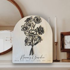 a wooden plaque with flowers on it sitting next to a clock and candlesticks