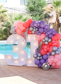 balloons are arranged in the shape of the number thirteen and placed next to a swimming pool