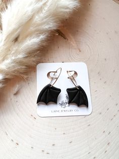 a pair of earrings with black bats hanging from them