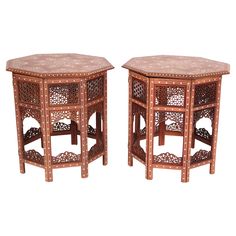 a pair of wooden tables with intricate carvings on the top and bottom, sitting side by side