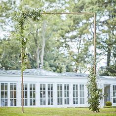 an outdoor ceremony setup with greenery on the ground and white building in the background