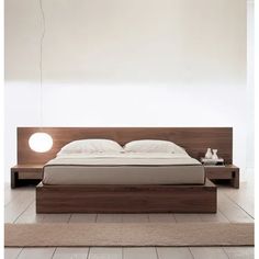 a bed sitting on top of a white floor next to a wooden headboard and night stand