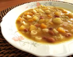 a white bowl filled with soup sitting on top of a woven place mat next to a wooden table