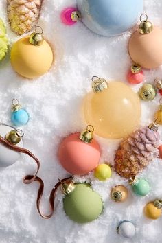 an assortment of christmas ornaments in the snow with one ornament hanging from it's side